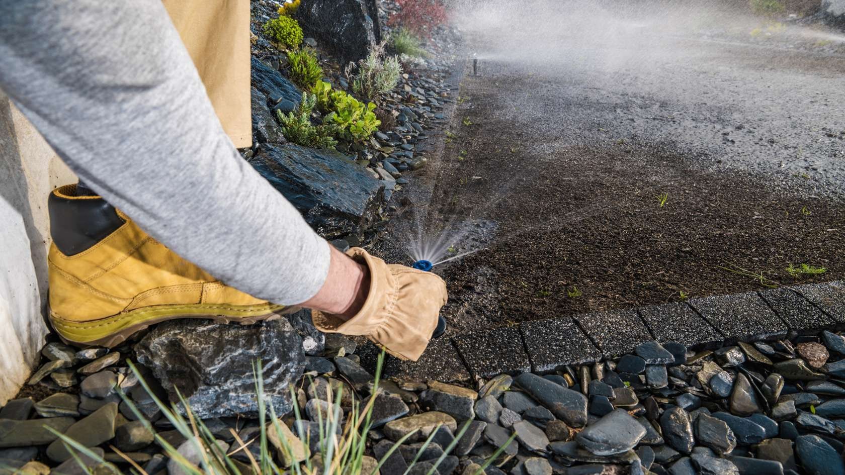 A person is spraying water on a rock garden