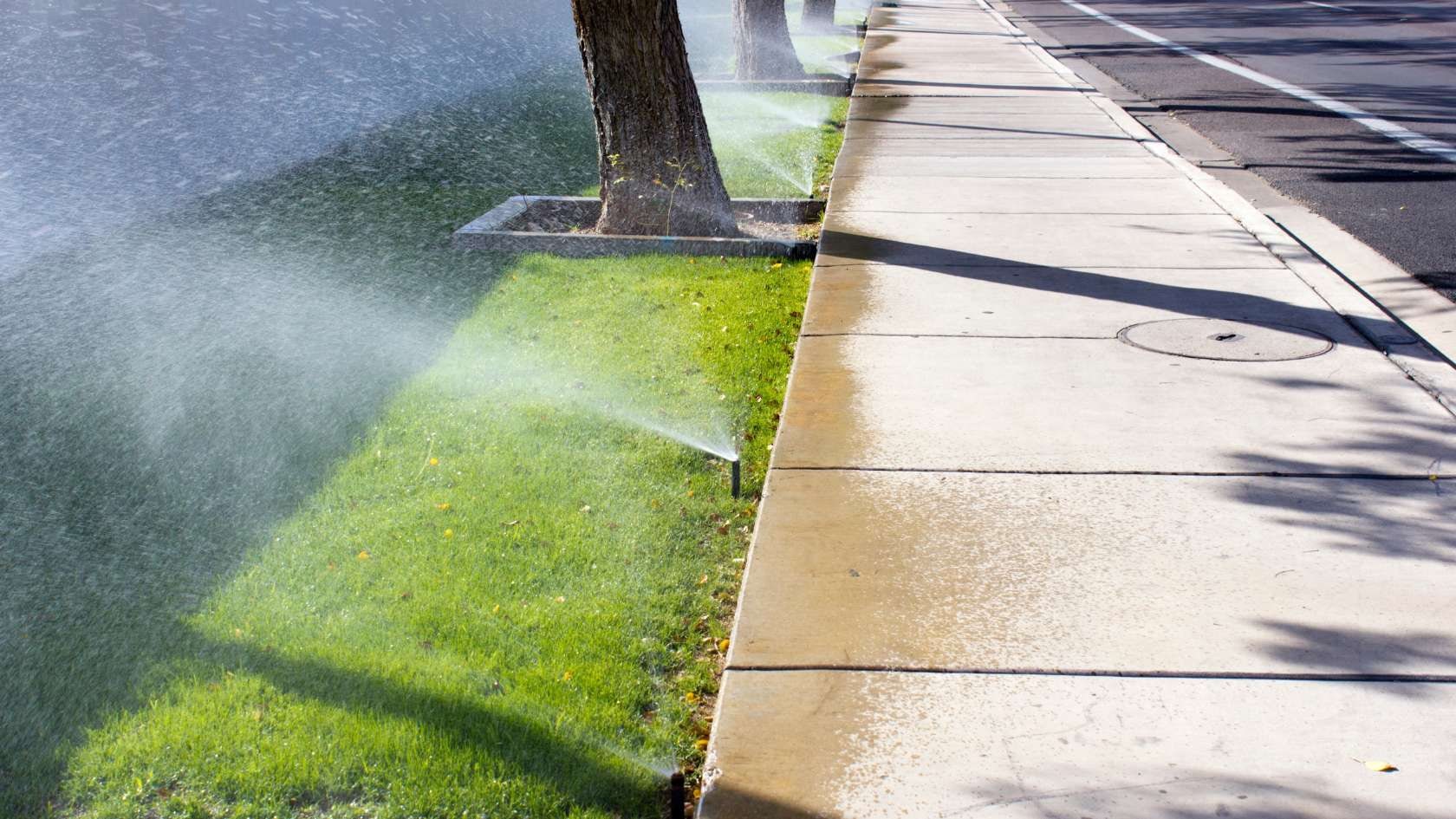 A fire hydrant spewing water on a sidewalk